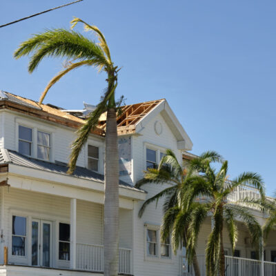 Damaged house roof with missing shingles after hurricane Ian in Florida. Consequences of natural disaster.