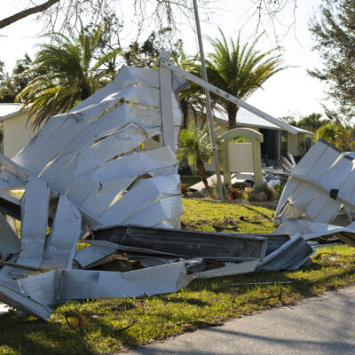 Scrap metal disposed in heaps on street side after hurricane severely damaged houses in Florida mobile home residential area. Consequences of natural disaster.